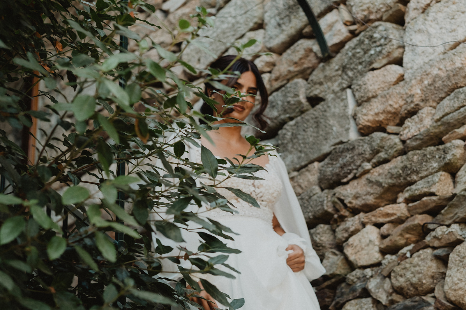 Kika com o vestido de noiva junto a uma parede de pedra